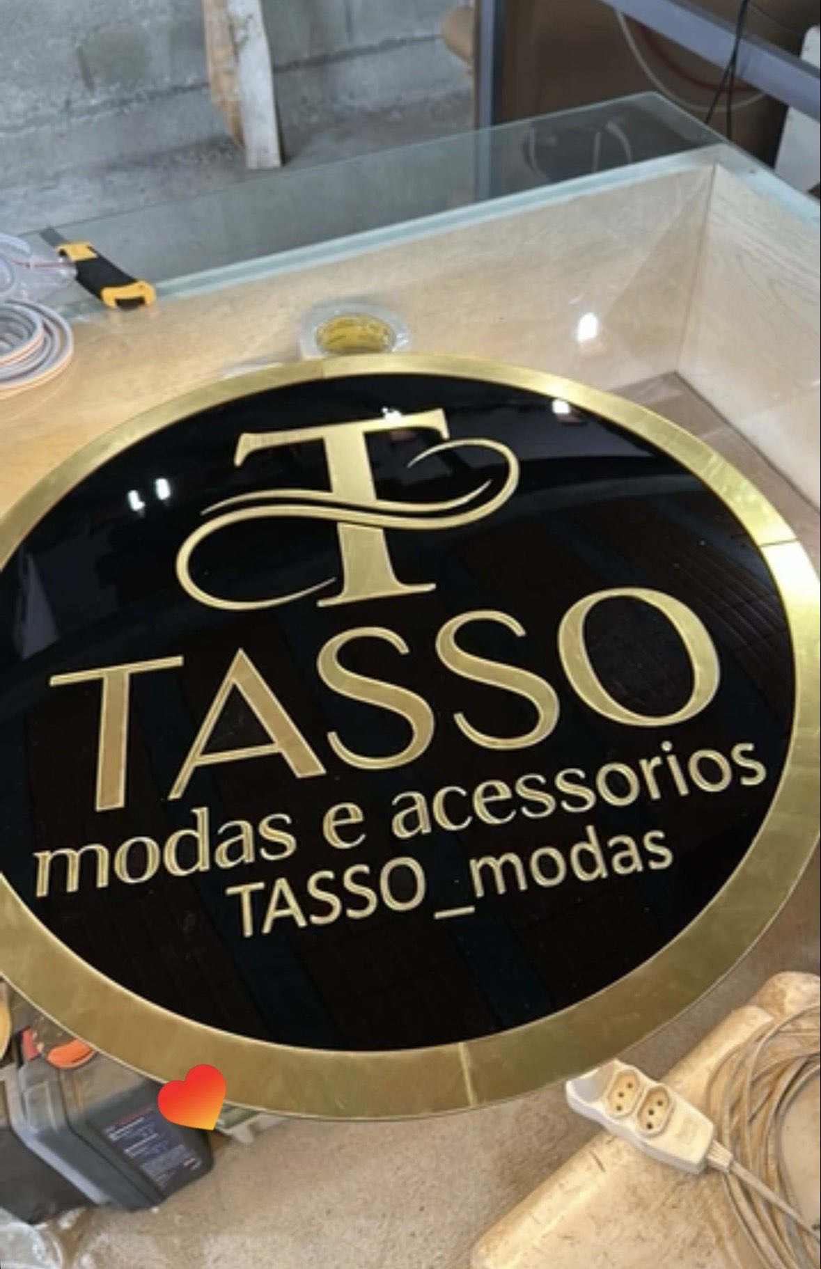 Placa redonda preta e dourada Tasso Modas